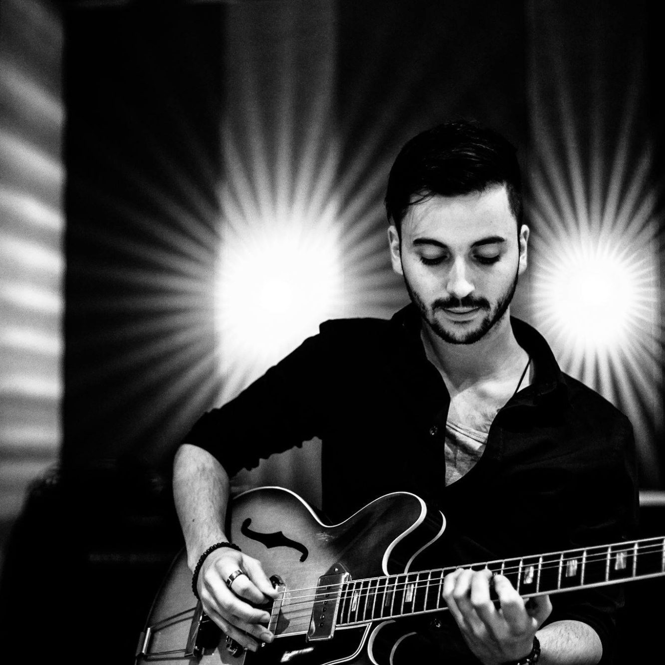 Mann spielt Gitarre in einem stilvollen, beleuchteten Raum.